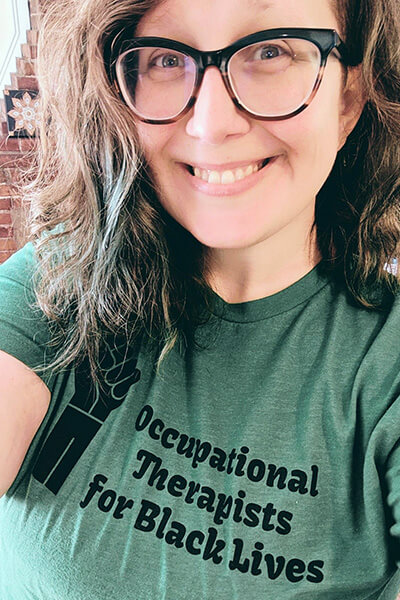 A selfie of Sarah wearing a green T-shirt that says: occupational therapists for Black lives